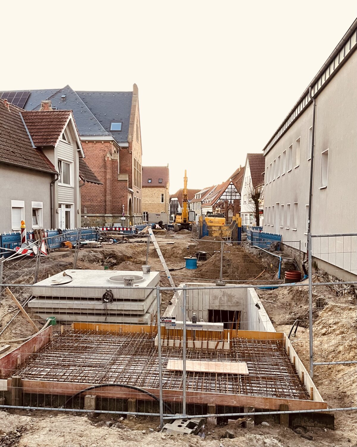 Eine aufgerissene Straße in Wiedenbrück. Man sieht viel Sand, Baugitter, mehrere Bagger und viele Bauzäune. Links erkennt man das Amtsgericht.